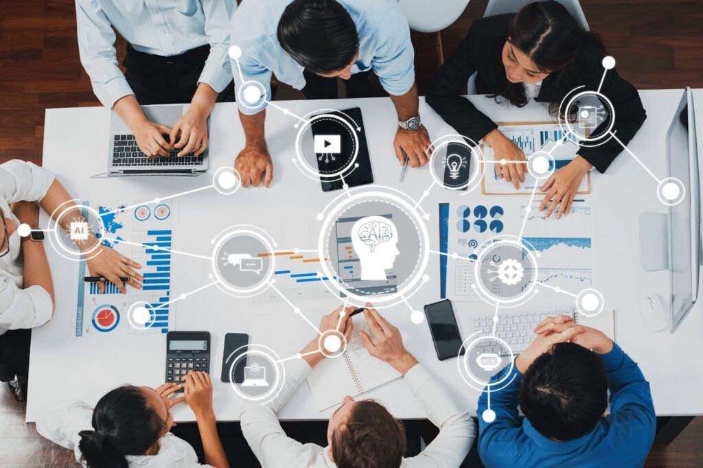 A team working at a table with laptops, charts, and digital icons representing AI and data analysis.